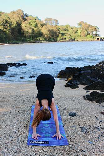sports woman in black outfit doing yoga beside body of water person